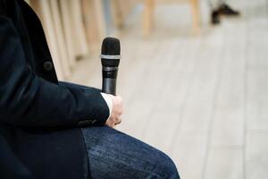 Stage microphone in the hands of a person, a guy speaks at a conference, training, conversation with the audience. photo