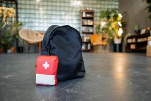 A first-aid kit is on the floor along with a backpack, travel medicines, and a black bag. photo