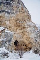 Kalimuskan Rock and Salavat Cave in Bashkiria, entrance to the cave in the mountain, winter landscape, nature of Russia. photo