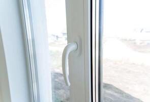 Plastic window, white handle on the double-glazed window, house decoration elements, double glazing. photo