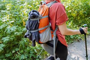 A tourist walks along the road in the forest, camping equipment, equipment on a hike, a backpack for things. photo