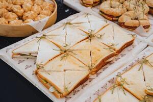 Delicious sausage sandwiches, triangular slices of bread, ham sandwiches, an appetizer on the table. photo