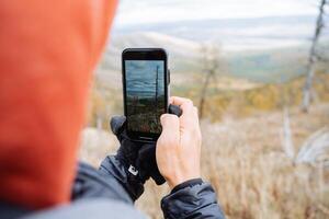 The guy takes pictures with his phone of the nature around, beautiful landscape, mobile photography in the mountains. photo