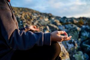 Chinmudra on the hand, fingers folded in mudra, meditation in the mountains, a fragment of a body part, the hand rests on the knee, yoga in practice. photo