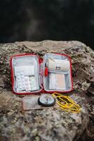 Tablets for pain, an elastic bandage in a roll, a compass on a rope, a red first-aid kit, a set of medicines. photo