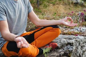 Meditation posture, legs crossed, sitting on a stone, hands folded to knees, outdoor recreation, yogic practices, Zen structure. photo