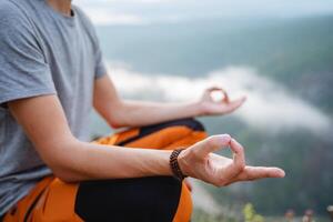 The practice of meditation sitting on top of a mountain in a space of emptiness. Isoterica and Zen, hands of a young man, a guy yogi. photo