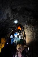 Tourists explore an underground cave, a group of people stuck deep underground, a karst mine, a staircase in a cave at the bottom of a well, a speleo expedition. photo