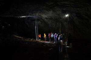 In a large cave there is a staircase leading to the course on the ceiling of the vault, a group of tourists visited the cave complex. photo