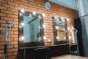 A mirror and two chairs in front of a brick wall photo
