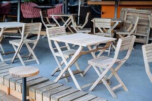 Wooden table with chairs in an outdoor cafe, a place for lunch on a summer day, a city restaurant on the sidewalk, an empty breakfast table. photo