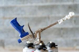 Dirty tools after the work of builders, spray foam stuck on the metal tube of the gun, industrial tools. photo