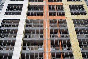 Insulation of the facade of the residential building. Construction works, laying mineral wool on the walls. Protection of the walls of the building. Thermal insulation from the outside. photo