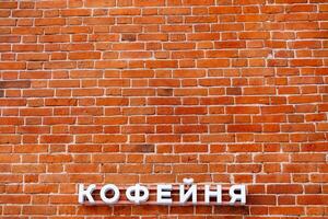 Minimalistic shot of a brick wall with sign. A coffee shop sign on the wall. Announcement on the facade of the building. Red brick masonry. photo