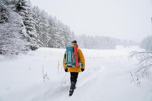 Brave traveller.Hiking backpack on the back of the traveler. Snowy forest and rocks. Climbing the mountain in winter. Survival in the wild. photo