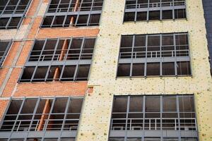 The fasade of the house can be seen with thermal insulation. yellow insulation should be mounted on the wall of the building. Metal aluminum profile for glass installation. photo