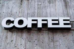 The sign is a coffee restaurant, the word hangs on the wall of the cafe, white printed letters, three-dimensional advertising symbols. photo