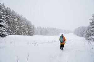 Hiking backpack on the back of the traveler. Snowy forest and rocks. Climbing the mountain in winter. Survival in the wild. photo