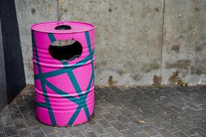 A pink trash can with a blue and green design photo