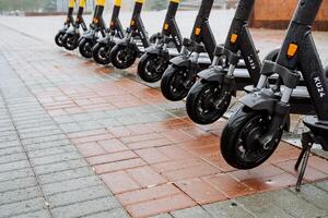A row of scooters are lined up on the sidewalk photo