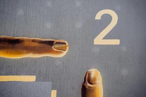 A hand is pointing to a number two on a wall photo