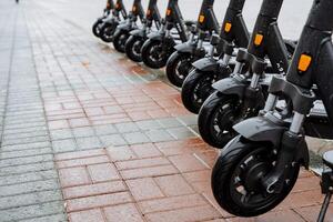 A row of electric scooters are lined up on a sidewalk photo