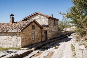 A couple of old stone houses with a skull roof. Settlements in mountainous areas, a country road in the mountain. Rest in a warm country. Hot summer photo