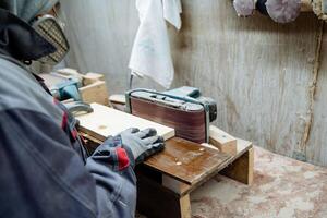 The carpenter processes a bar of wood. Work in the workshop. The process of creating an object from wood. photo