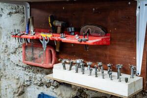 Rack with working tools. A set of nozzles for drilling. Processing of wood and other material. Installation for sawing boards. Equipment in the carpentry workshop photo