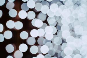 White blurry light from garlands on a dark background. Bright shot. photo