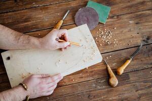 The carpenter draws with a pencil on the board. hand holds a pencil, carpentry workshop, sketch of the future product photo