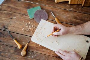 Pencil sketch on the board, carpenter prepares the material for work, pencil in hand draws a line, workshop at home photo