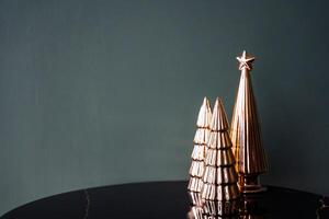 Minimalistic shot of decorative small trees of golden color. Statuette of the Christmas tree. Decorations for the christmas tree. New Year and Christmas atmosphere. photo