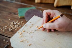 The carpenter draws with a pencil on the board. hand holds a pencil, carpentry workshop, sketch of the future product photo