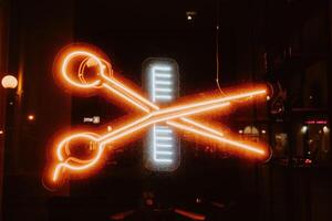 Neon sign in the form of scissors and combs. Bright photo in the dark