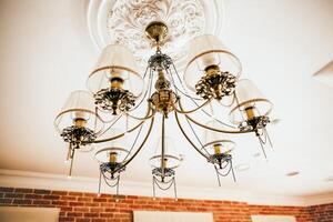 The chandelier hangs on the ceiling. Beautiful vintage lamp in the interior of the apartment. apartment design. lighting in the house. Boho style. Elegant fixture. photo