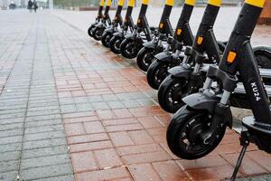 Parking of electric scooters on the street. The wheels of the scooter are in a row. The concept of eclogical transport. Black color of scooter photo