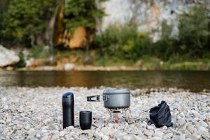 Cooking on a hike on the banks of the river. The concept of tourist cuisine. Tableware for tourists. Minimalism in travel. photo