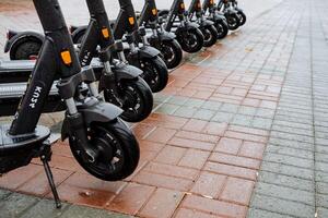Parking of electric scooters on the street. The wheels of the scooter are in a row. The concept of eclogical transport. Black color of scooter photo