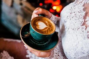 cup of coffee in the hands of the unveted. vivacity in the morning. heart drawing on a foam cappuccino. have a cup of coffee. close-up from above photo