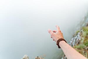 hand with a Rudraksha bracelet on the background of fog, fog in the mountains, morning photo