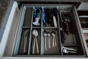 A set of Cutlery in a drawer. Correct placement of knives, forks and spoons in the drawer. Order in the kitchen. The concept of order in the house. photo