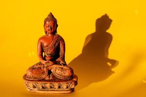 Buddha on a yellow background. figurine of a Buddha statue brown. jade Buddha, meditation, yoga photo