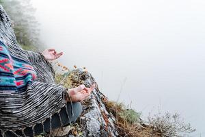 fingers folded in mudra against the background of mountains and fog, a state of peace and tranquility, Zen, yoga in nature photo