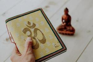 a brown ceramic Buddha figurine, yoga-themed attributes, a diary for recording yoga classes, a symbol of peace and tranquility, Zen photo
