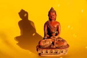 jade Buddha figure on a yellow background. yoga in a meditation position. tranquility and peace. the concept of minimalism photo