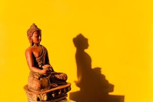 jade Buddha, Buddha figurine on a yellow background, shadow of the Buddha in the sun photo