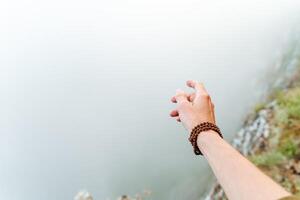 hand with a Rudraksha bracelet on the background of fog, fog in the mountains, morning photo