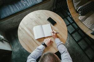 Man writing in notebook at table photo