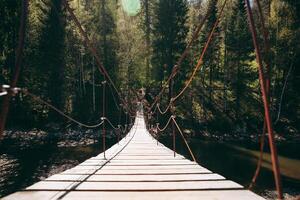 hanging wooden bridge over the river, suspended pedestrian bridge over the canyon, artificial crossing sunlight, travel photo